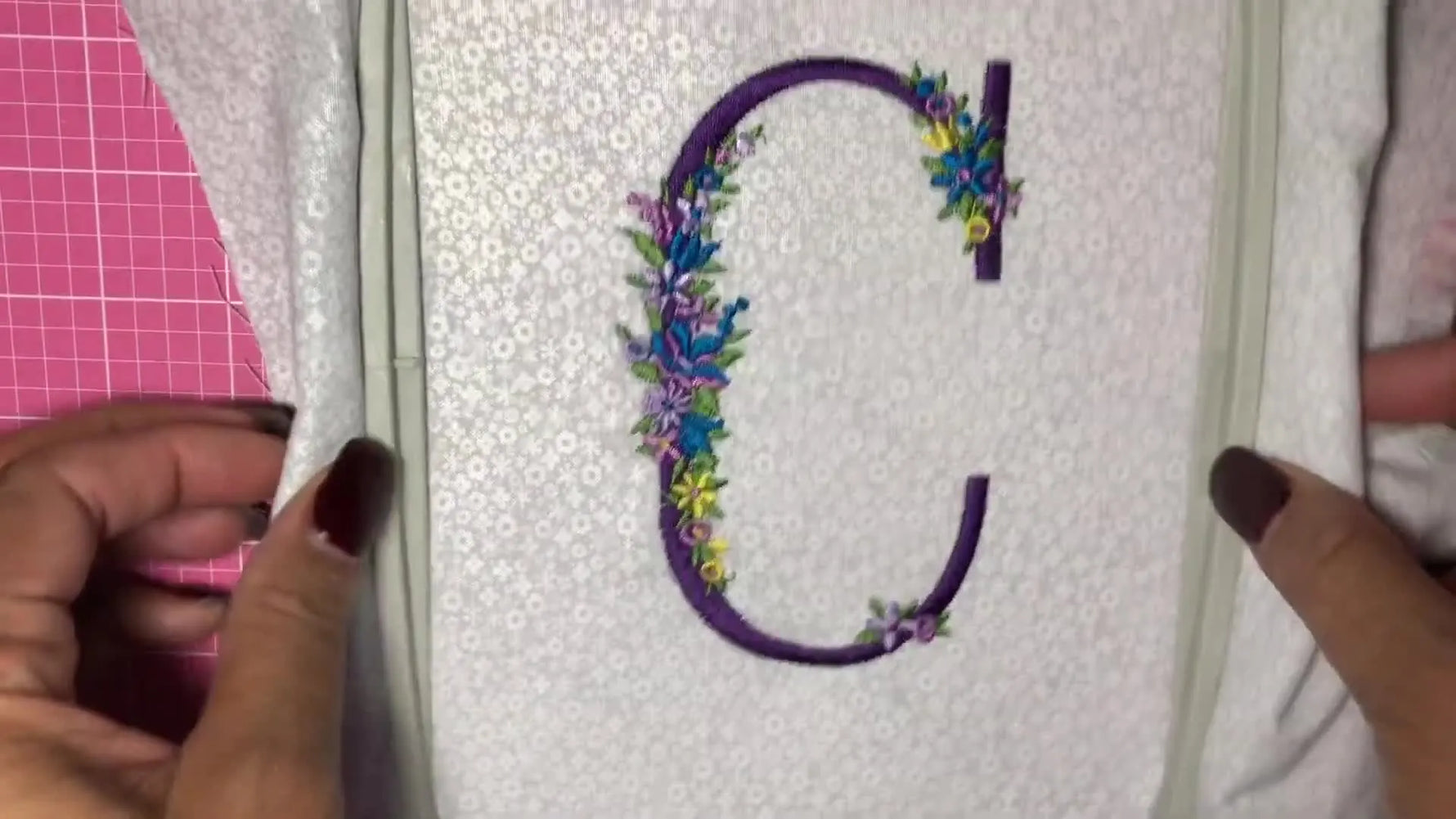 A close-up of a floral letter “C” monogram stitched on a Brother PE800 while still held taut in the standard 5x7 hoop.