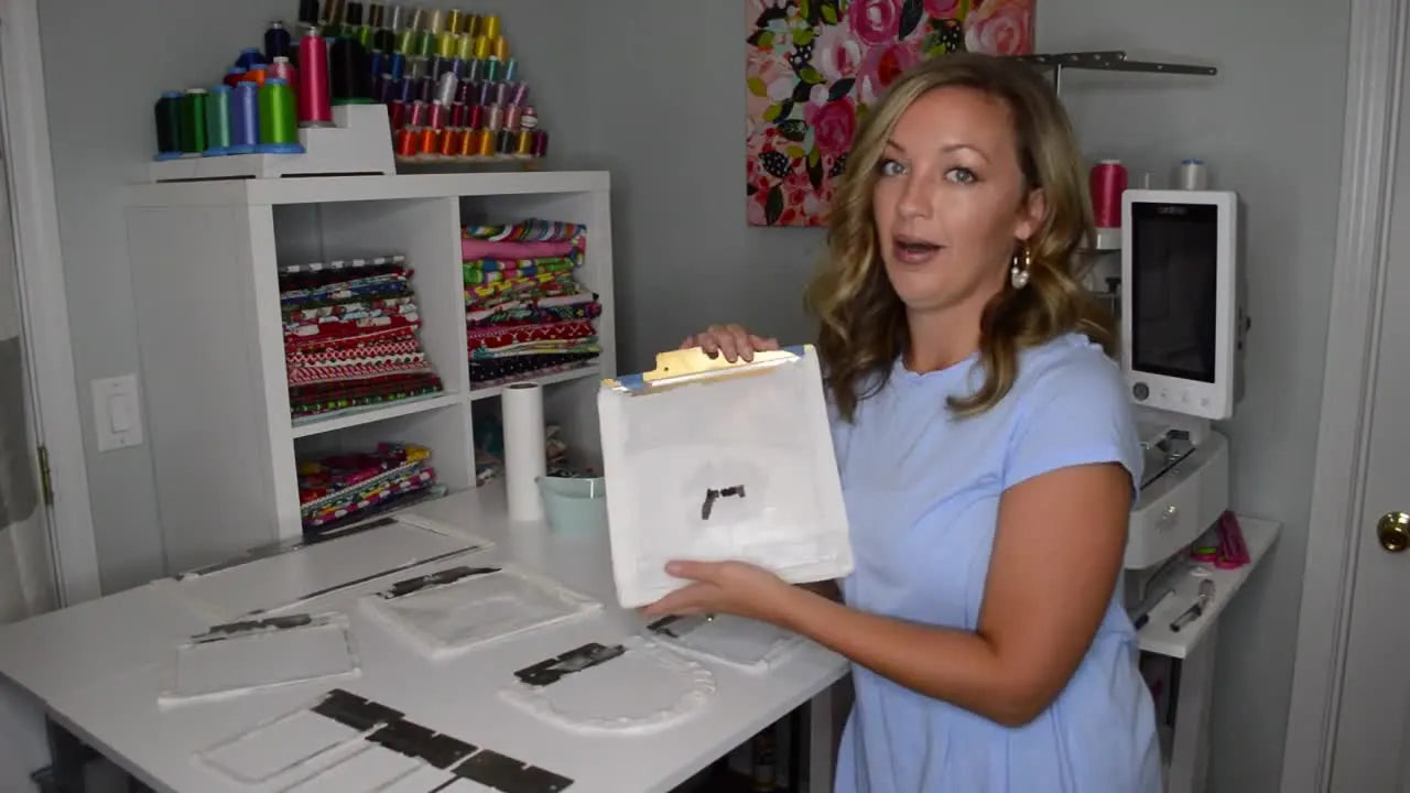 A large 7x14 Fast Frame is held up in front of a multi-needle machine to show the oversized stitching area used for big names and pajama flap projects.