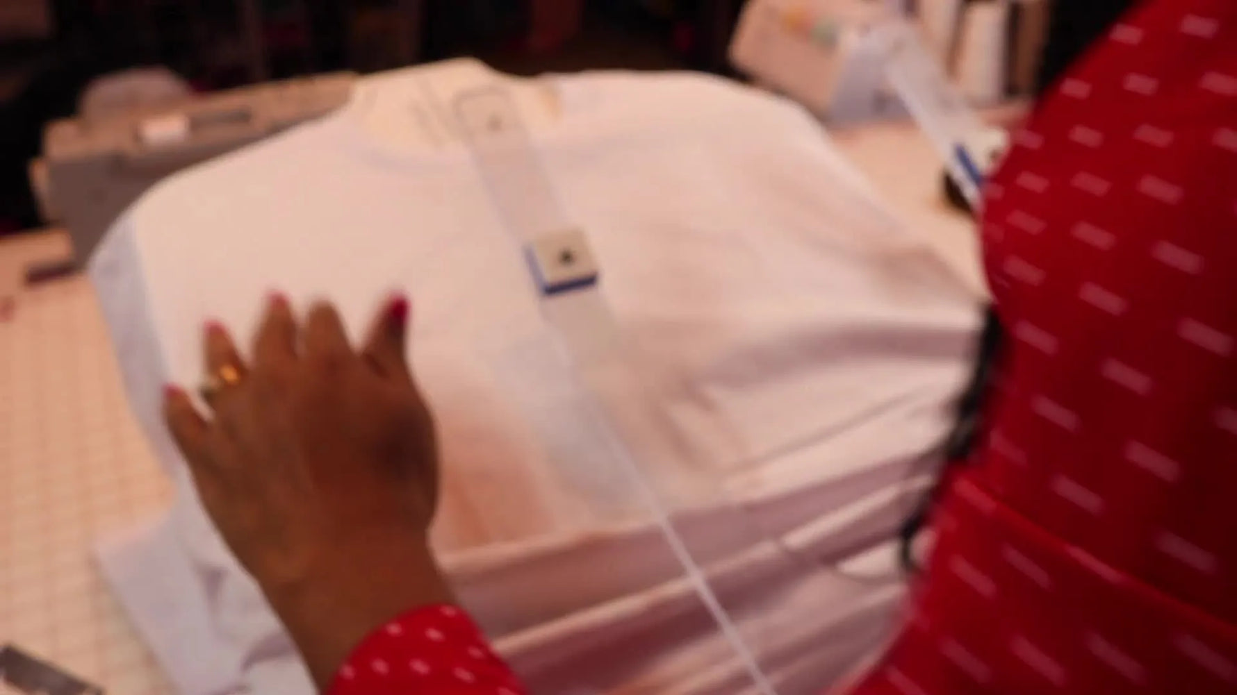 A heavyweight white T-shirt is smoothed and aligned on the Hoop Master board at the collar mark E, ready for consistent left-chest hooping.