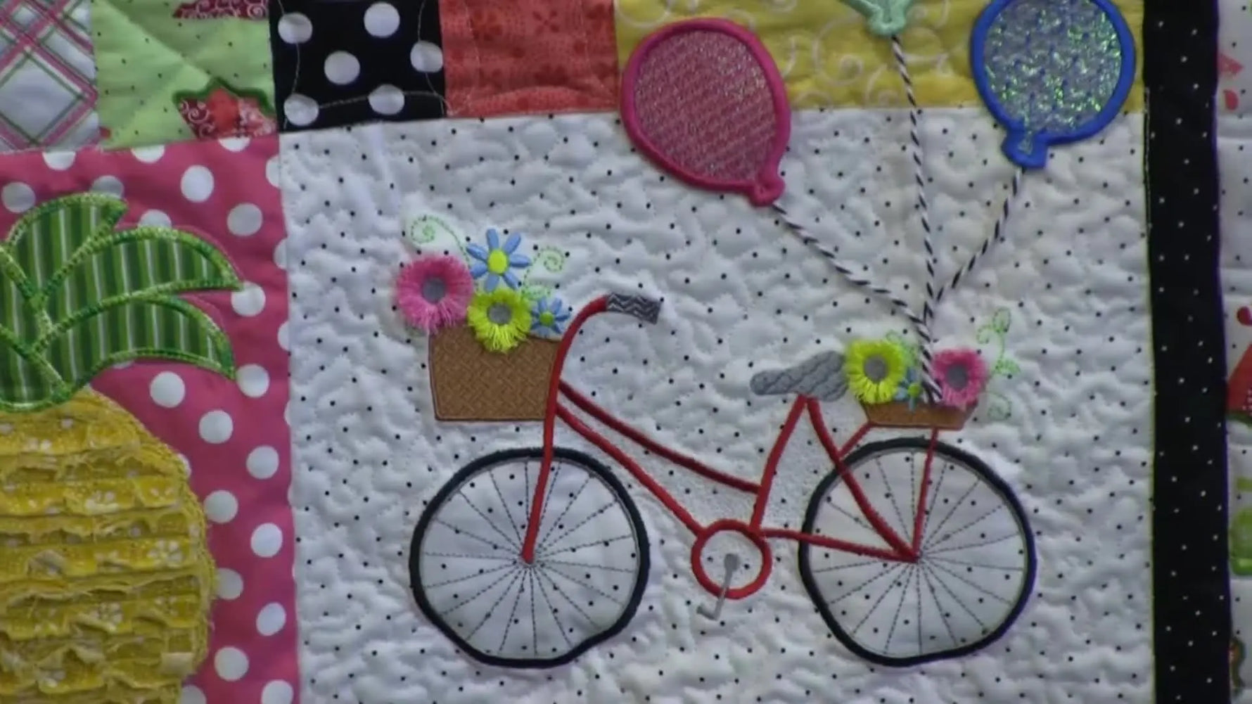 A close-up of the red bicycle quilt block with layered details, showing the crisp stitching and dimensional embellishments that define the Hello Sunshine quilt.