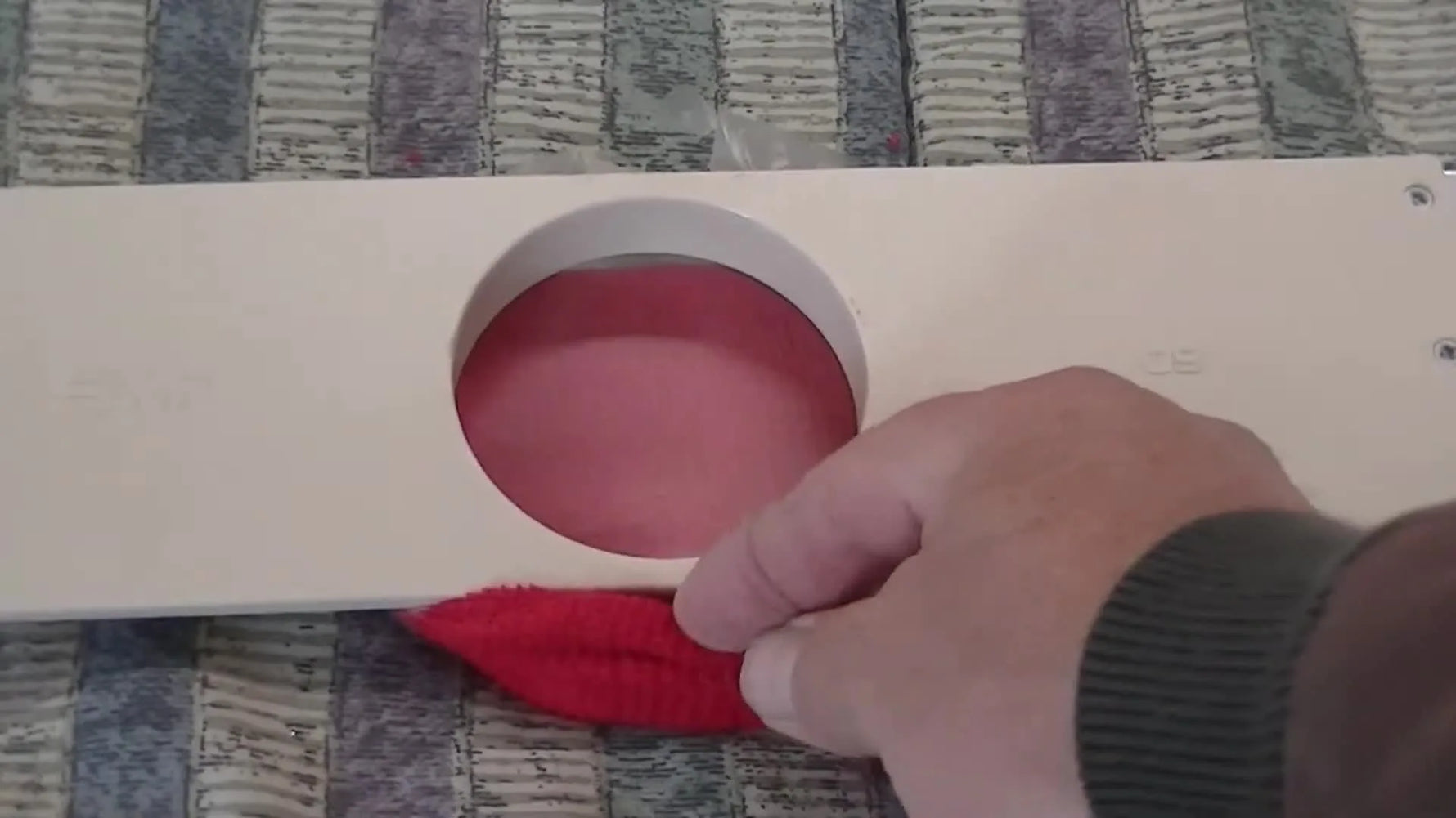 Close-up of the wristband’s bottom layer being pulled back over the hooping station tab to isolate the embroidery surface.