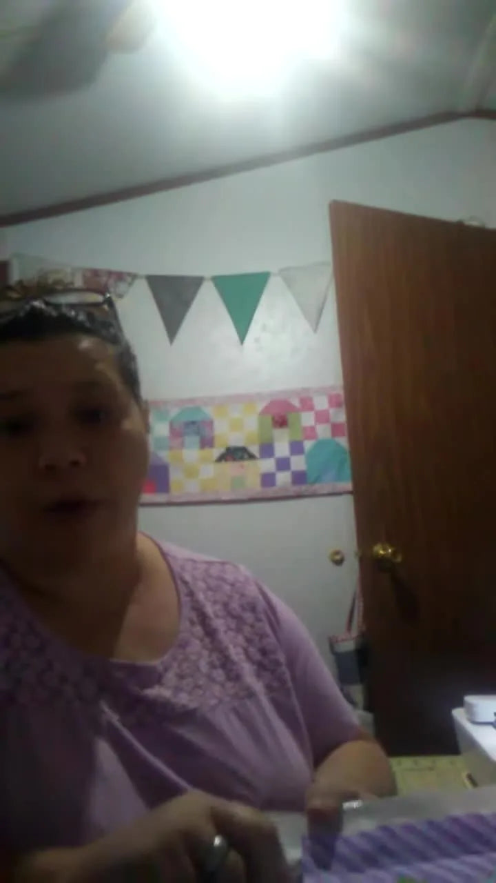 The finished “E” carrot appliqué block is held up in the hoop, showing clean satin stitching and a ready-to-finish quilt-style square.