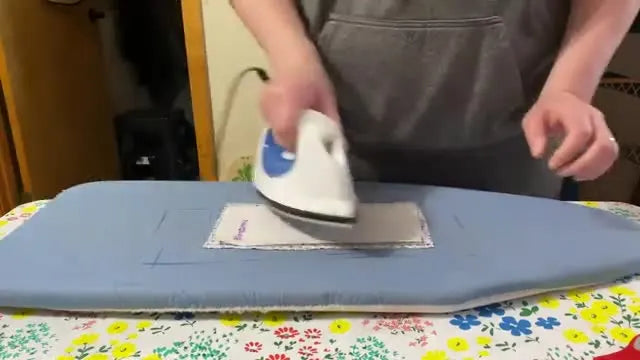 A close-up of an iron fusing HeatnBond Lite to the wrong side of fabric, showing the exact pressing setup for appliqué prep.