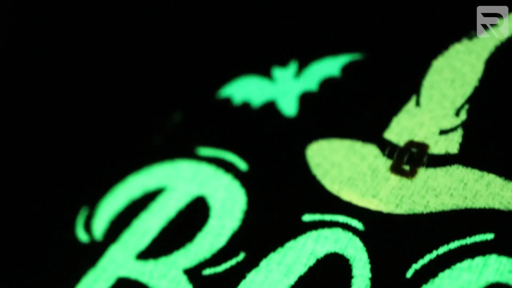 A black tote bag with a glowing “BOO” embroidery design photographed in the dark to showcase glow-in-the-dark thread impact.