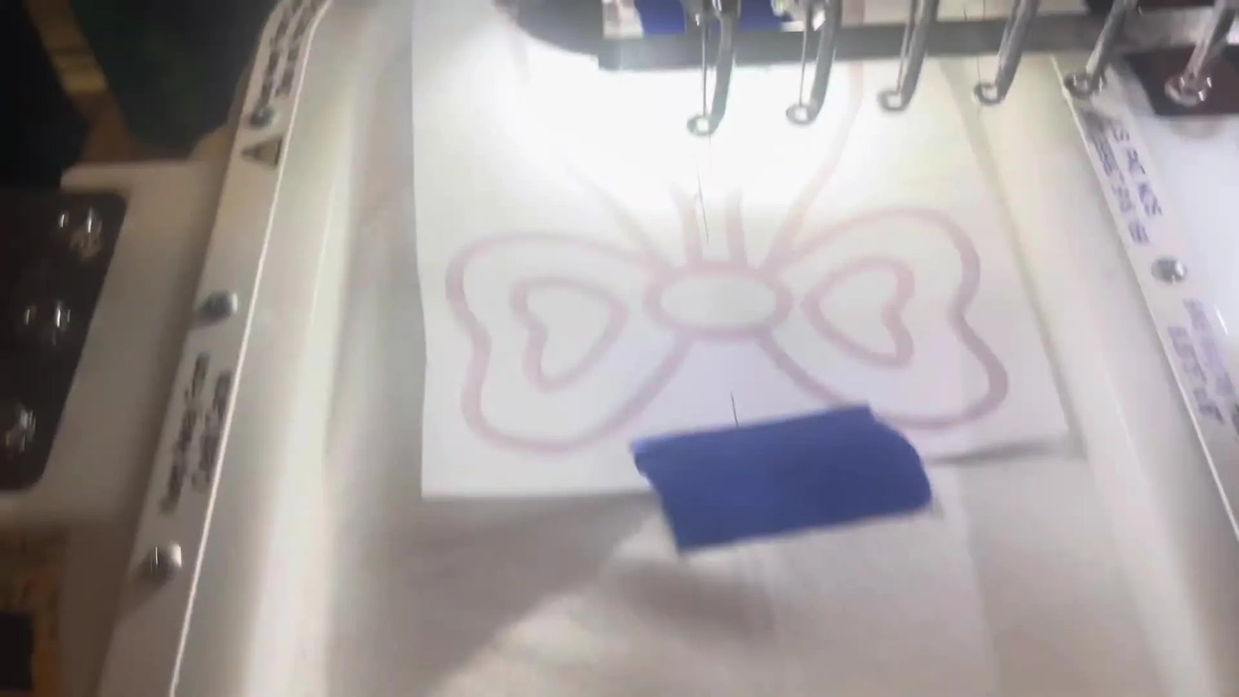 A Janome MB-7e checks center alignment with a 9x6 magnetic hoop loaded, using a paper template as the placement reference.