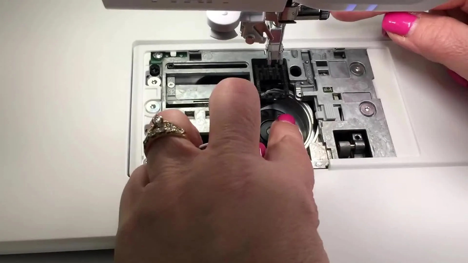 A close-up of the Pfaff Creative Icon bobbin case being aligned under the small metal tab—the critical seating step that prevents tension issues.