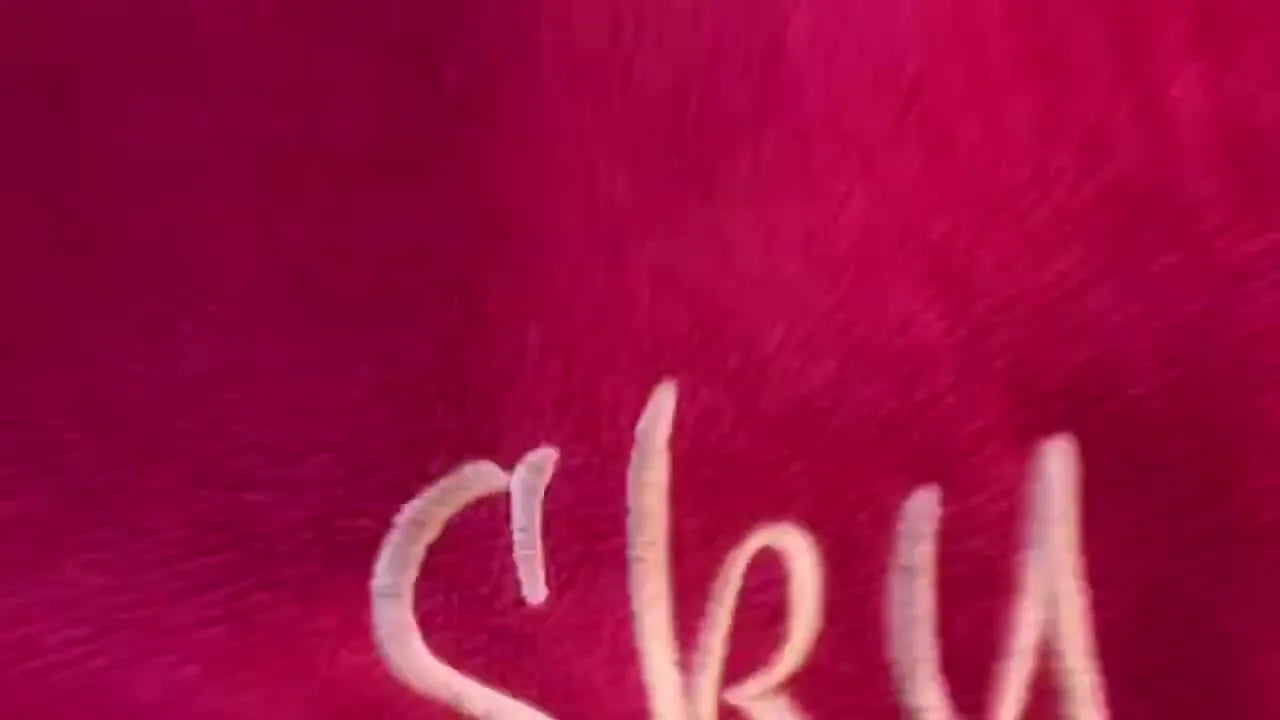 A finished script name stitched in light pink on a magenta terry beach towel, shown flat-lay for a clean final reveal.