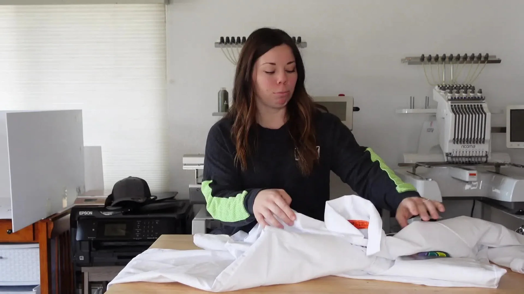 Woman holding up a white painter's jumpsuit with 'Professor B. LOON' and a colorful hot air balloon logo embroidered on the chest.