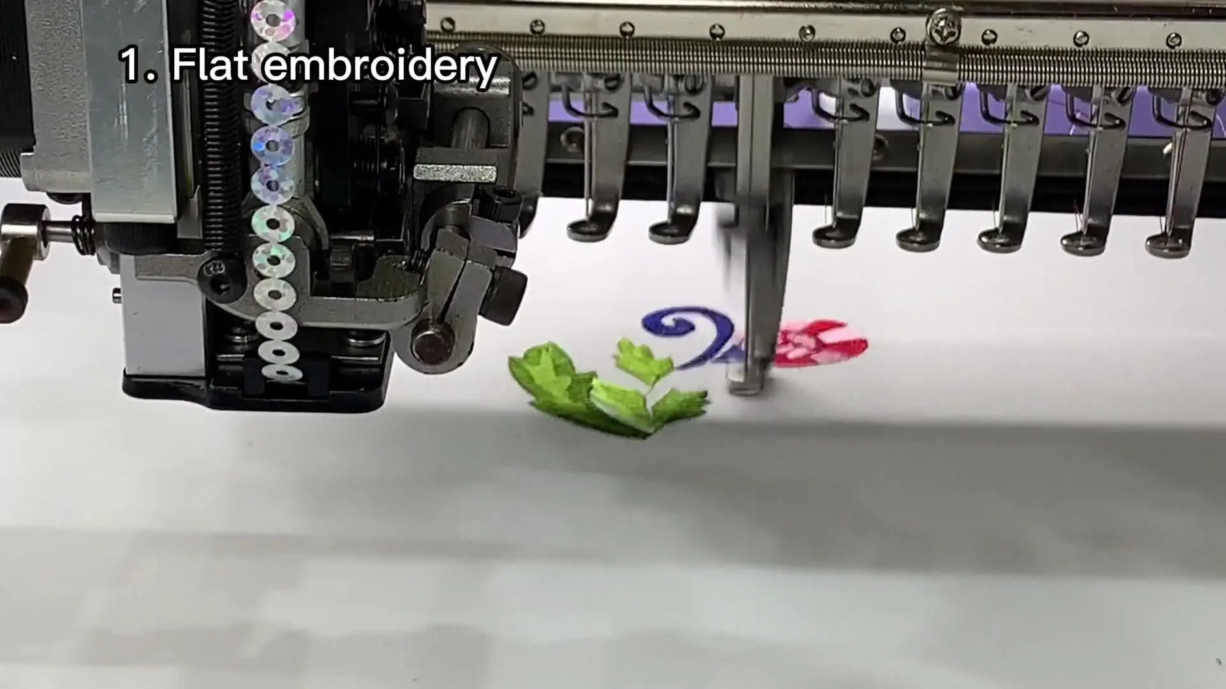 Close-up of high-speed flat embroidery stitching a flower pattern before the machine transitions into special-device work.