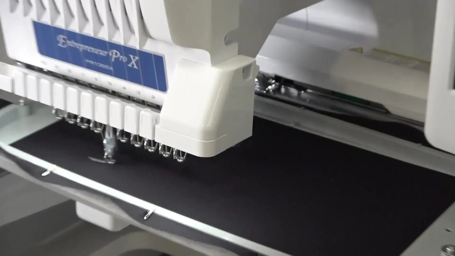 A close-up of the Brother PR1050X actively stitching the combined three-tile design on black fabric inside the 360×200mm hoop.