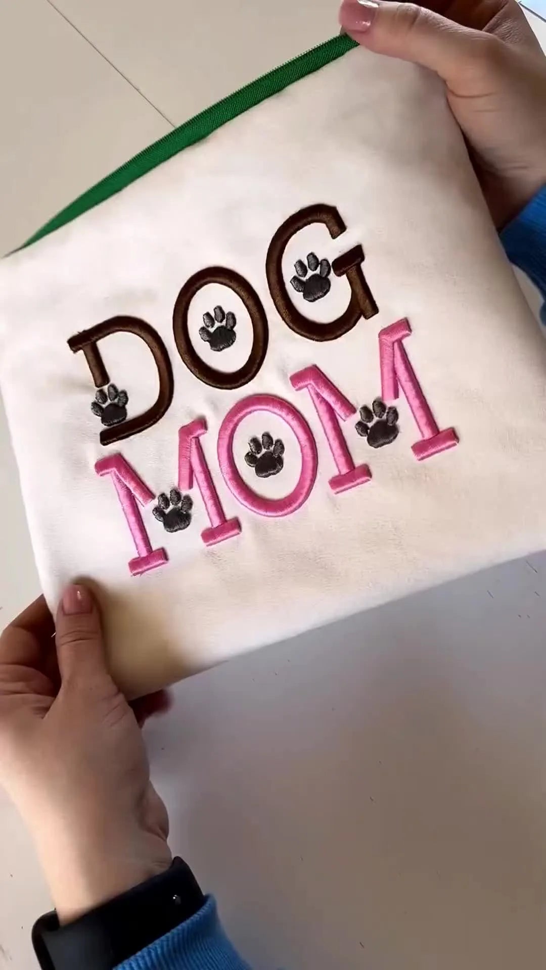 The finished “DOG MOM” 3D puff zipper pouch is held up, showing raised satin letters, paw details, and a clean zipper finish.