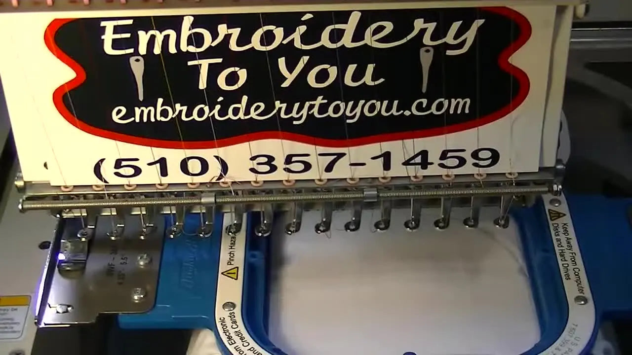 Embroidery machine with 'Embroidery To You' sign and polo shirt in hoop.