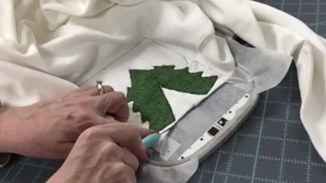 A close-up shows a seam ripper slicing the cutaway stabilizer under the V-split so trimming can be done flush without cutting stitches.