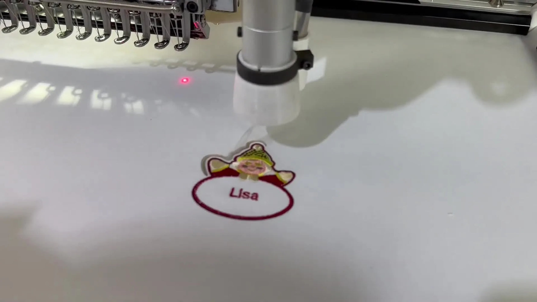 A close-up of the red laser dot tracing the patch outline right after embroidery finishes, showing the automatic switch from stitching to cutting.