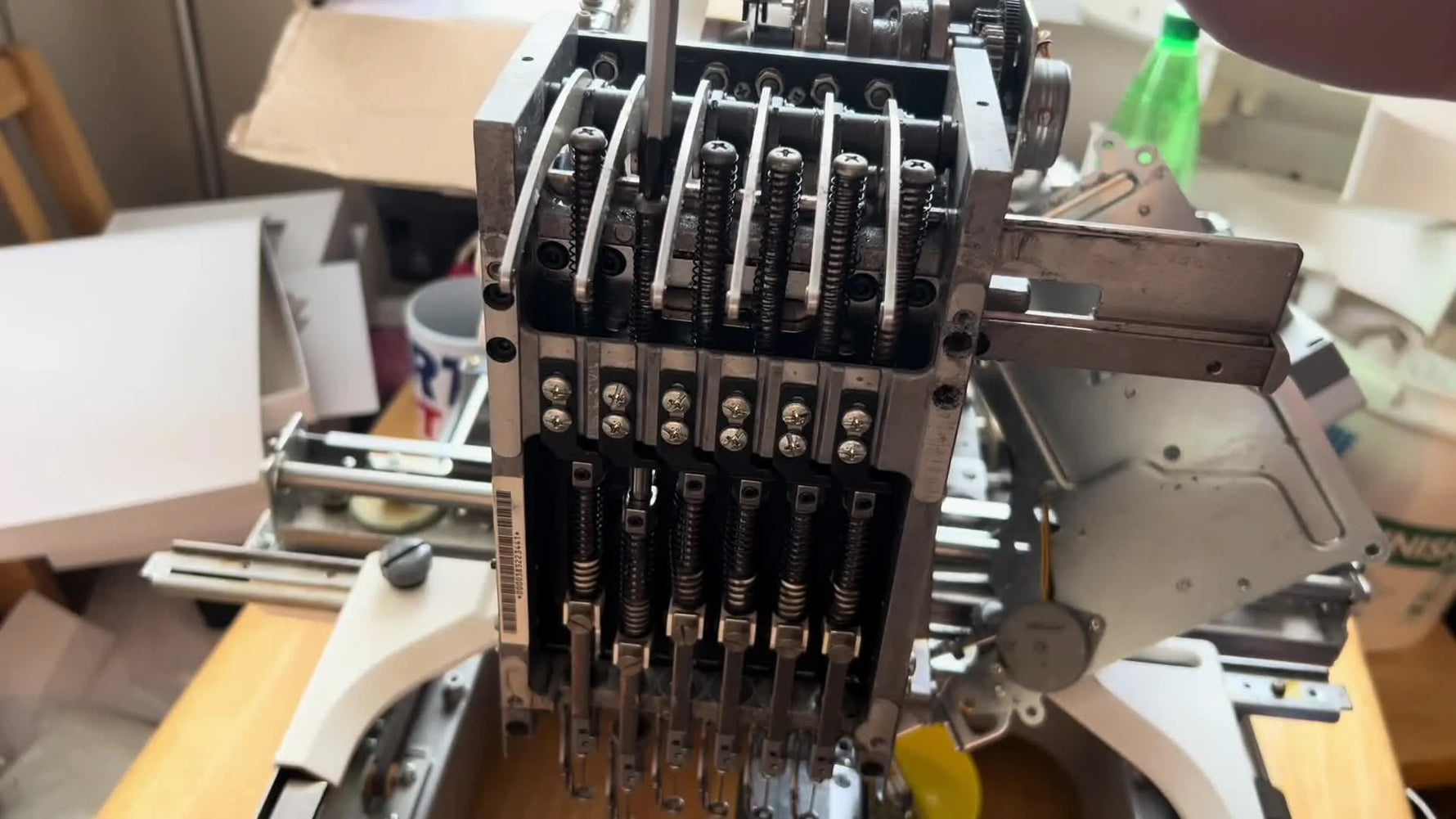 A technician uses a flathead screwdriver as controlled leverage to free a rust-seized needle bar inside a Brother PR 600 embroidery head.