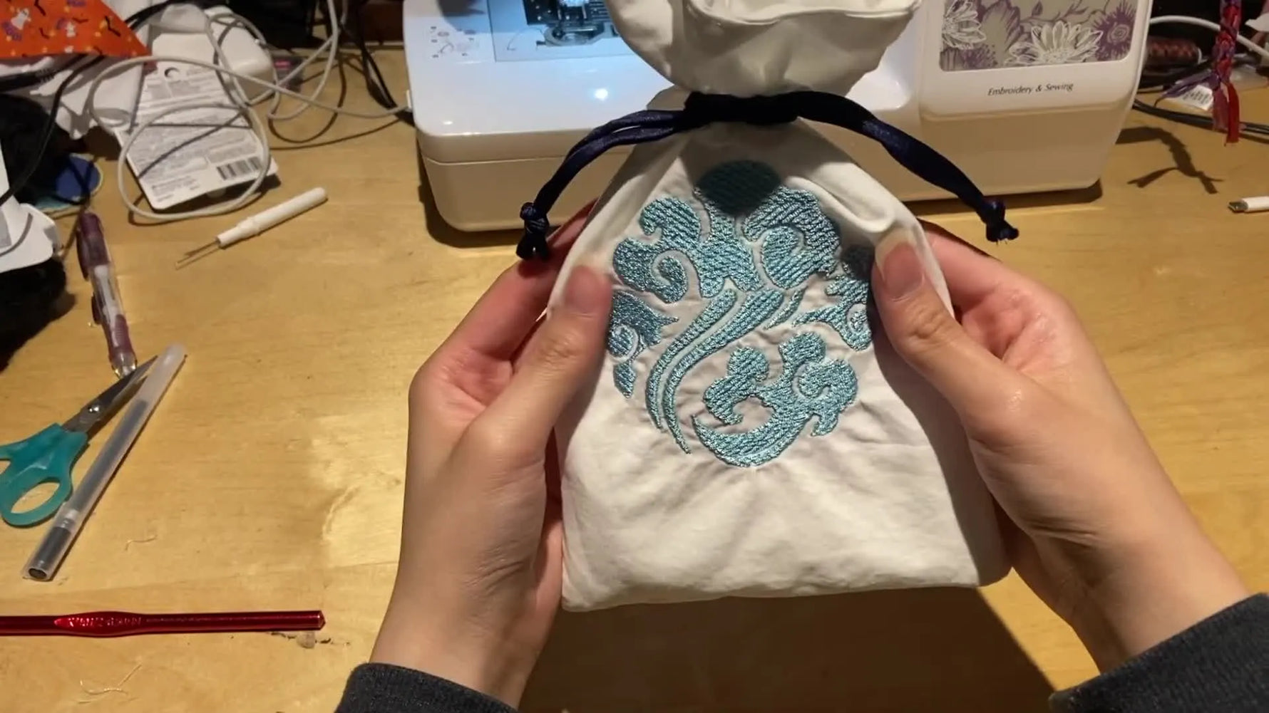 The finished reversible drawstring pouch stands upright, showing the teal crest and neatly formed drawstring channel.