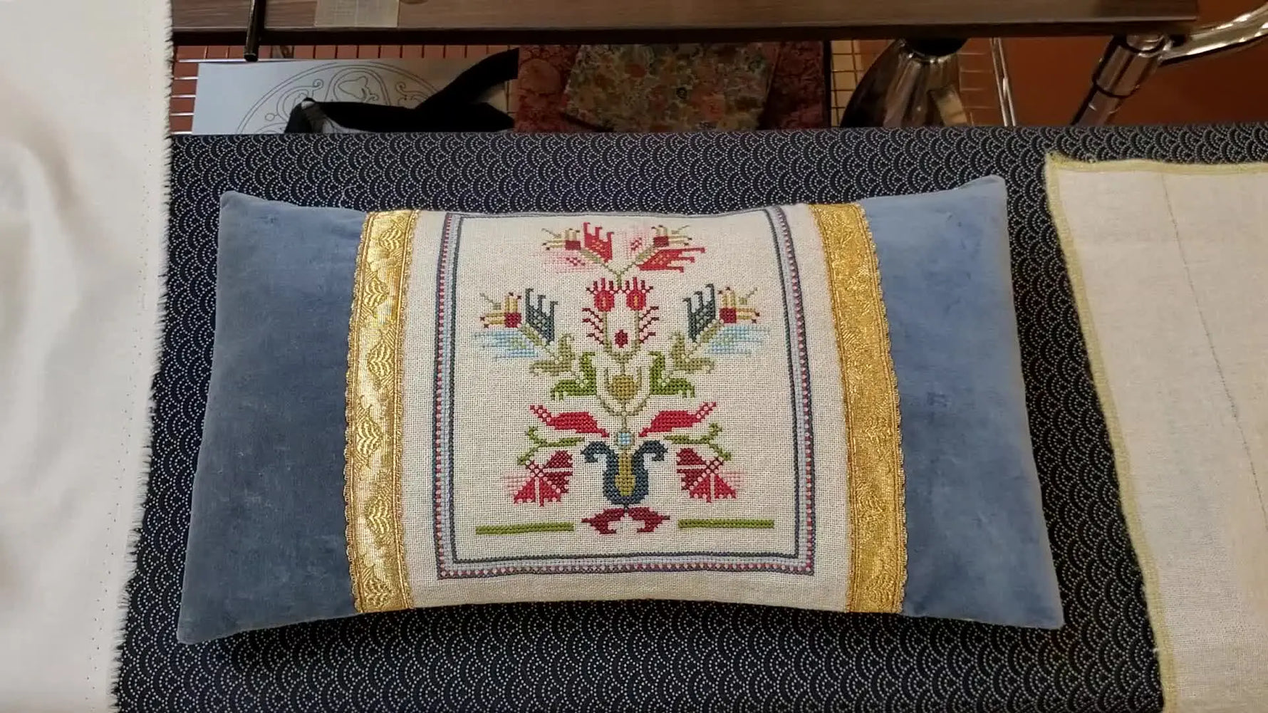 Finished embroidery cushion in blue velvet with gold trim