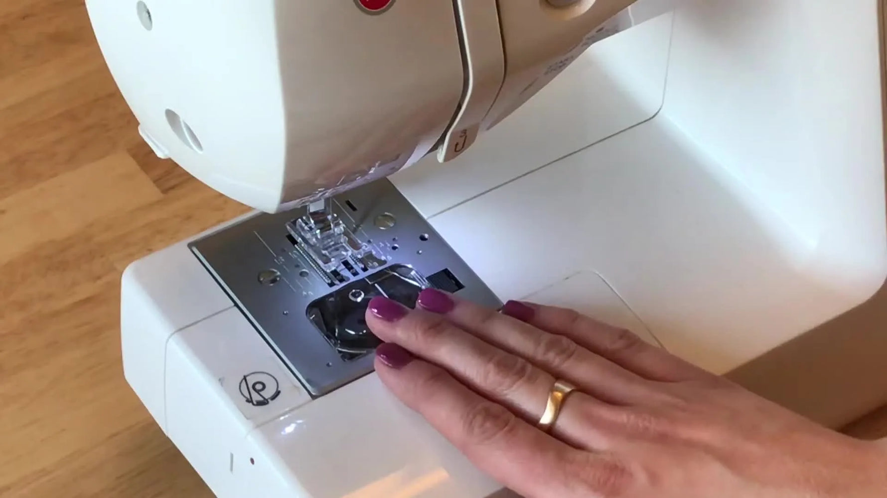 Close-up of bobbin thread being guided into the tension lip