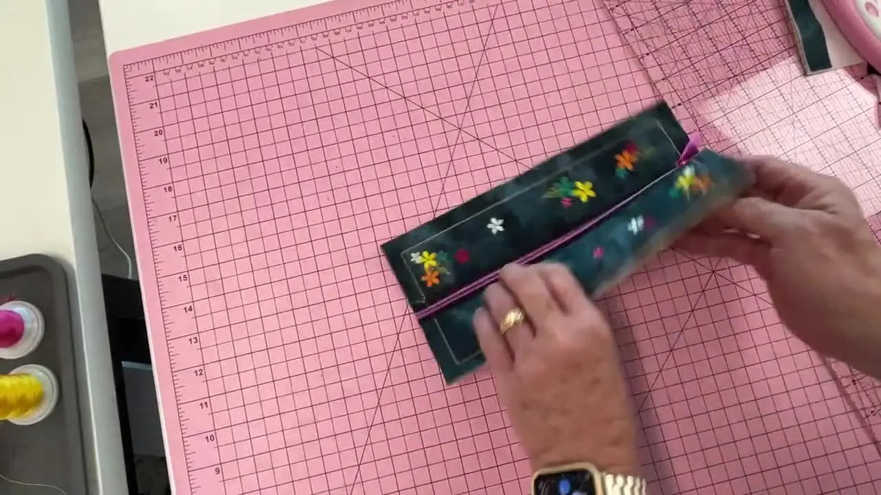 A finished in-the-hoop zipper gusset panel with floral embroidery and a centered zipper, ready to be trimmed to a clean 1/2-inch seam allowance.