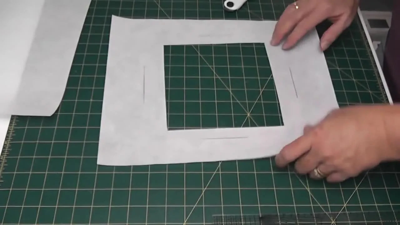 A large sheet of cutaway stabilizer with a clean rectangular window cut out, ready to be patched and reused in the hoop.