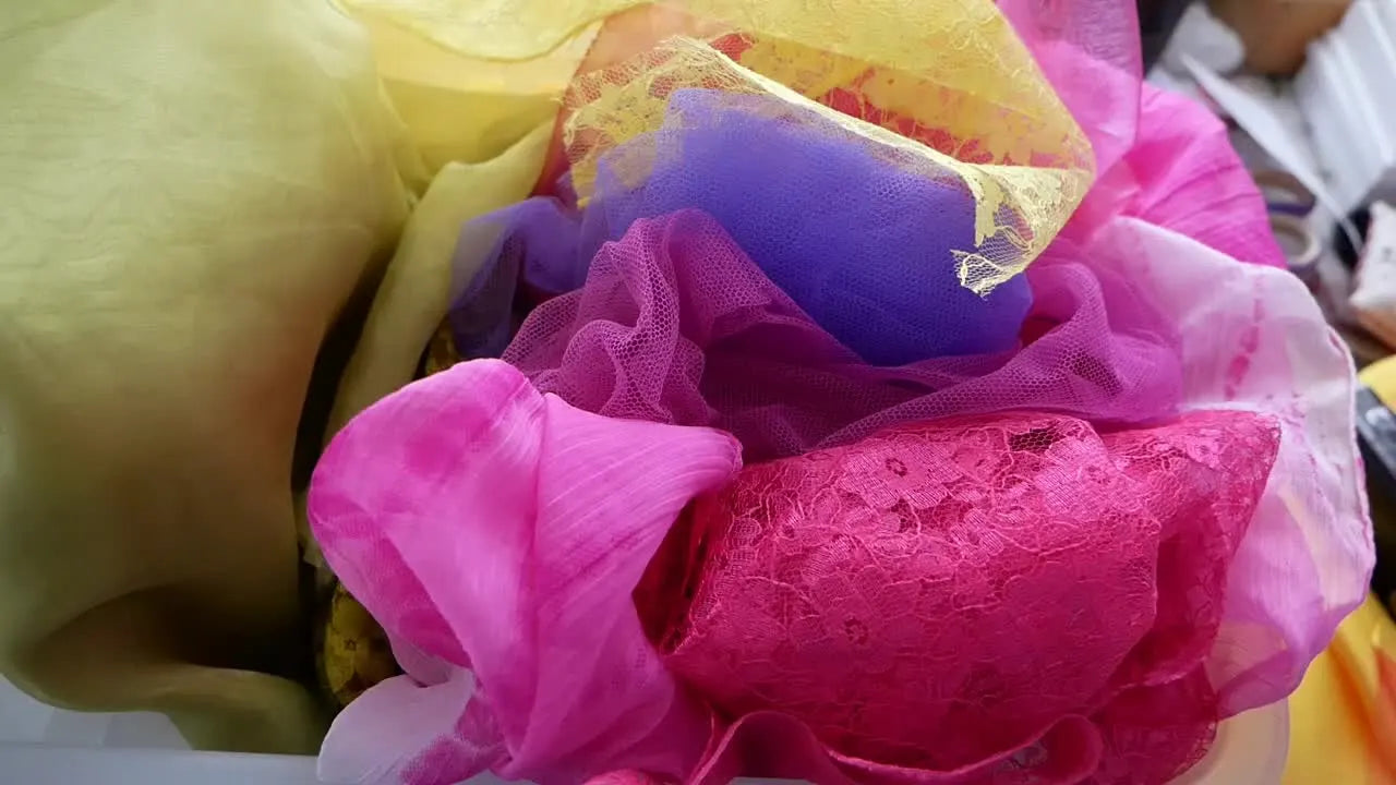 Hands sifting through colorful sheer fabrics and lace.