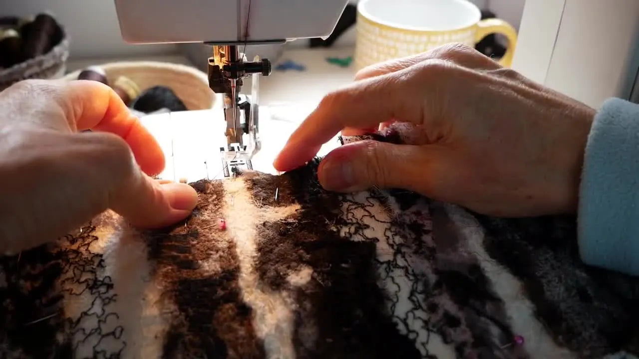Close-up of hands guiding fabric under a sewing machine needle for free-motion embroidery.