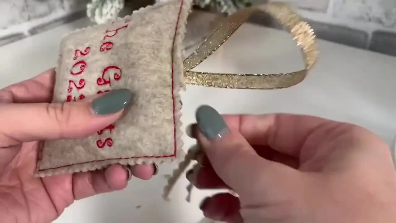 A close-up of the completed felt Santa ornament hanging, showing the embroidery detail and finished edge.