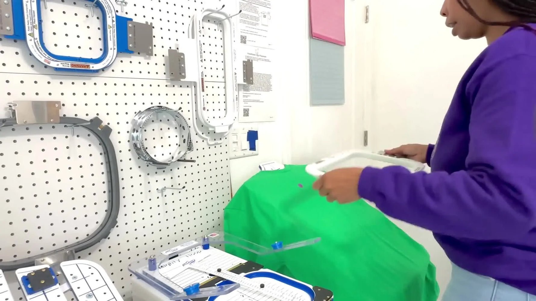A green T-shirt is snapped into a magnetic hoop on a hooping station, showing the fast, aligned hooping setup before stitching.