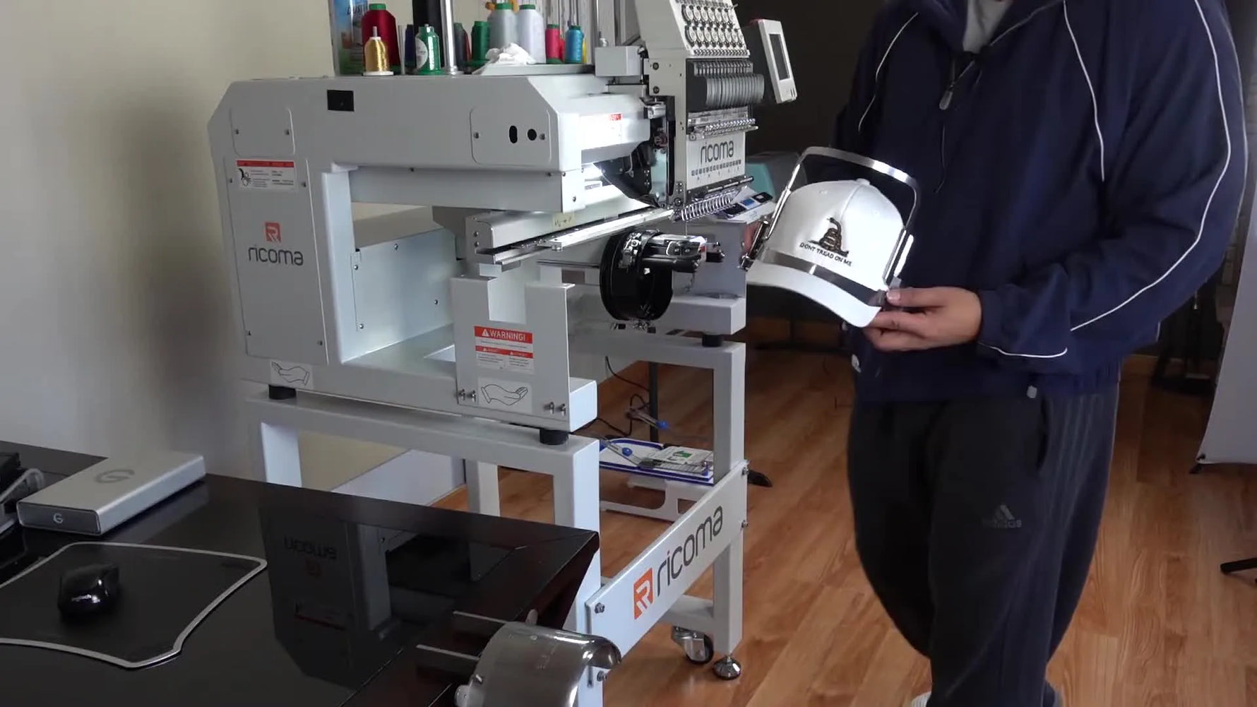 A close-up of the finished front embroidery still mounted on the cap driver, showing clean coverage and stable hooping tension.