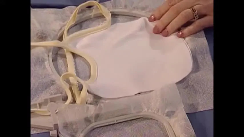 A baby bib is smoothed onto sticky stabilizer that has been hooped by itself, demonstrating the classic “floating” method for hoopless embroidery on knits.
