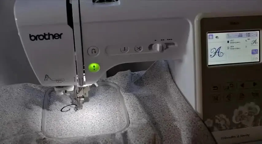 A close-up of the Brother SE625 start button glowing green, signaling the machine is ready to begin embroidery.