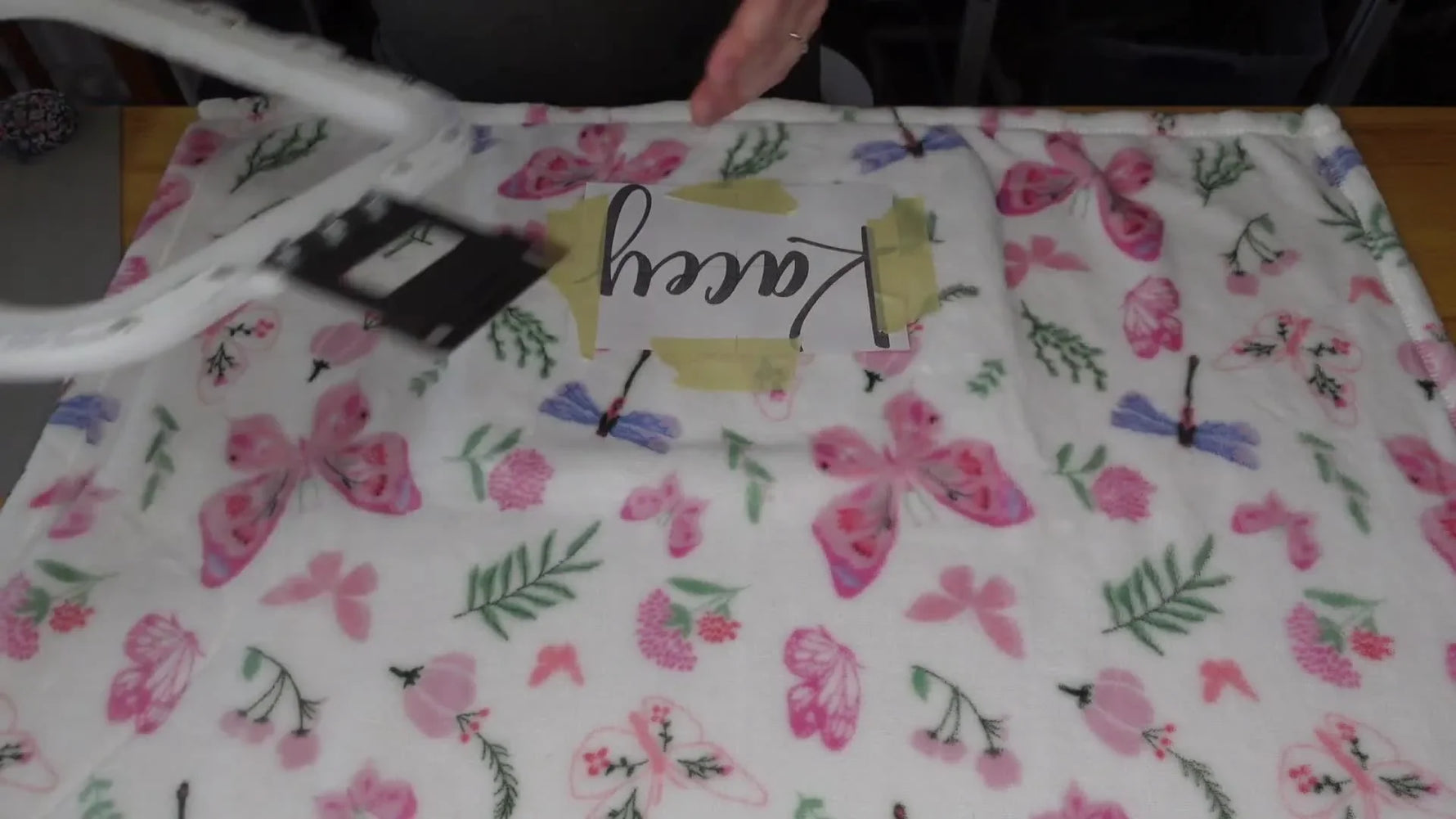 Hands hooping the blanket with a Mighty Hoop over the taped design.