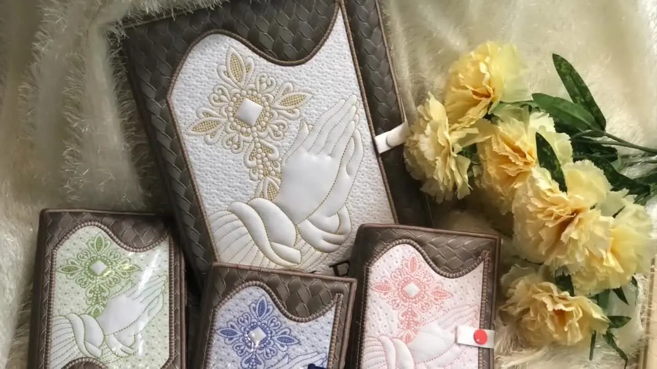 Finished ITH Bible book covers in various sizes and colors, showcasing different embroidery designs.