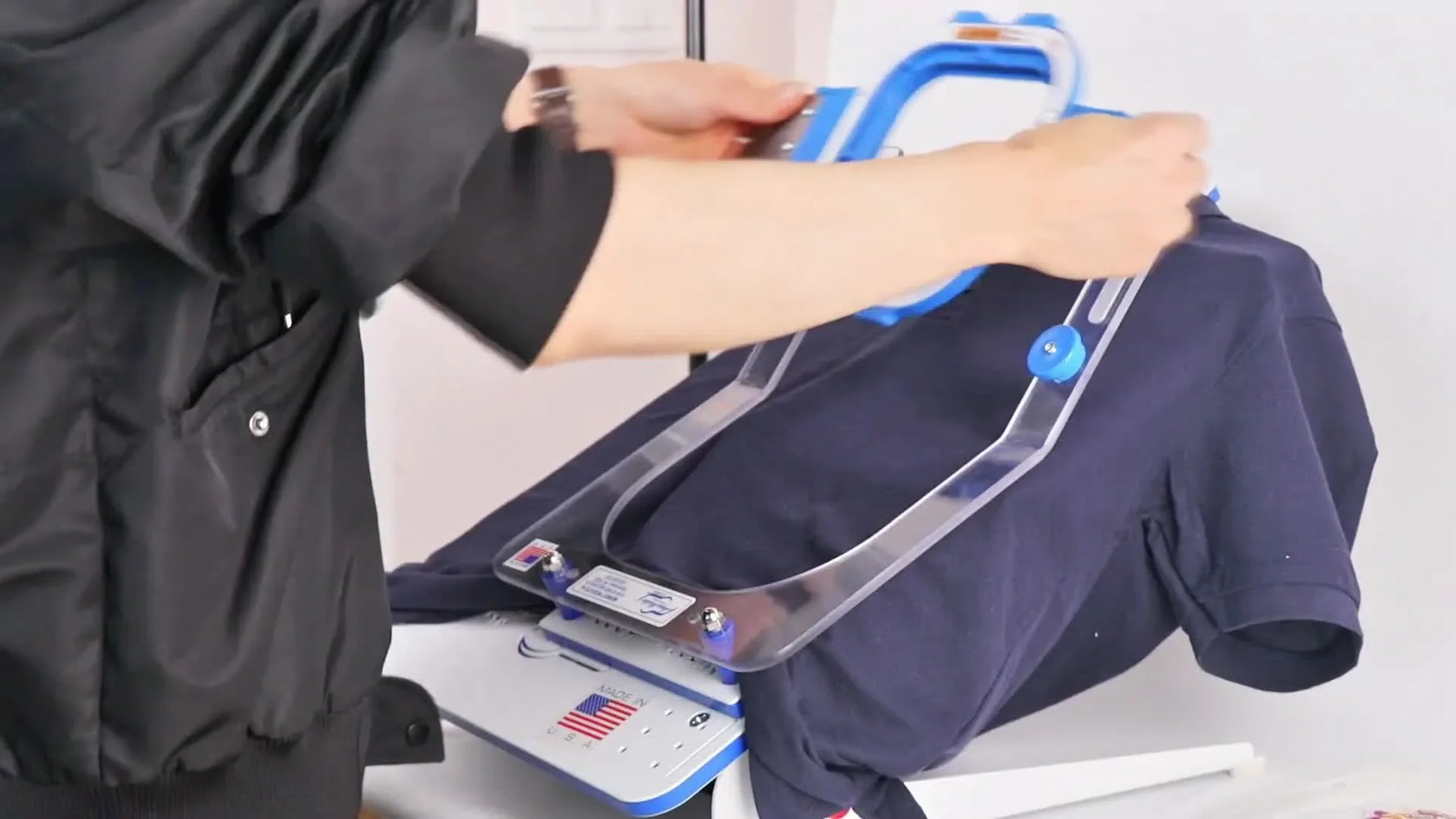 A blue magnetic hoop snaps onto a navy T-shirt on a hooping station, showing fast, consistent garment hooping for patch attachment.
