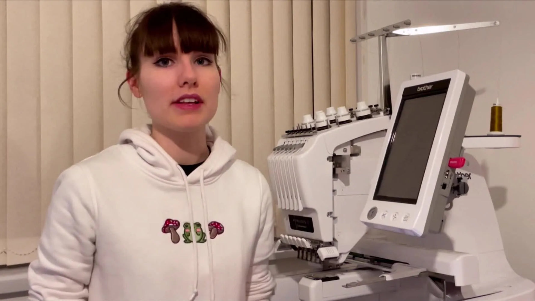 Two large embroidery hoops are held side-by-side, clearly showing the long-rectangle Brother hoop versus the square Happy hoop.
