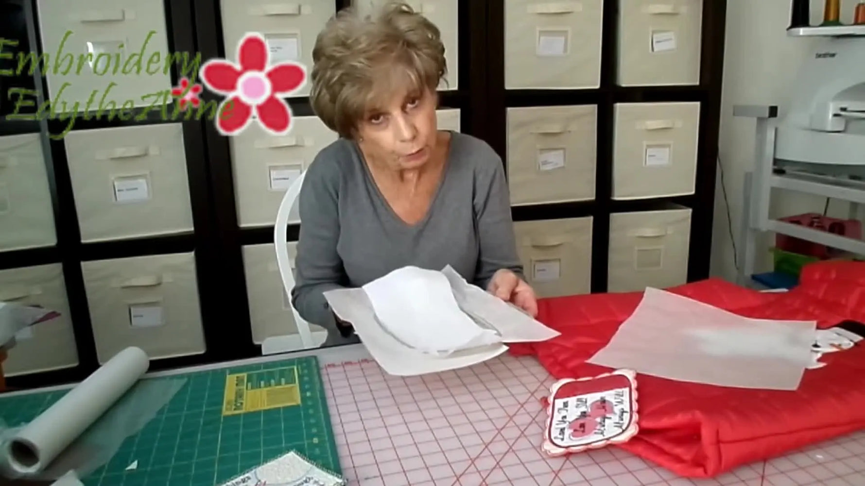 Hands slide a cut-away stabilizer sheet underneath a hoop that’s already hooped with fibrous wash-away, demonstrating the core “floater” technique.