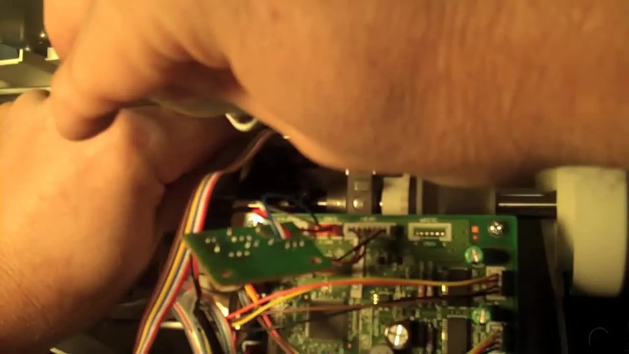 Close-up view of the encoder wheel centered inside the photo eye sensor gap during Brother PR-620 encoder reinstallation.