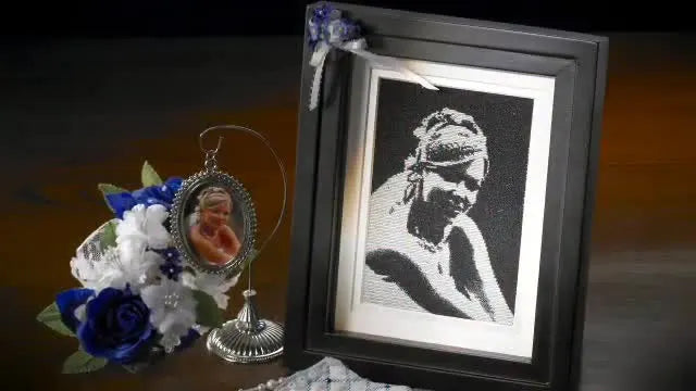 A framed embroidered baby portrait created from a black-and-white photo, showcasing the kind of result MasterWorks II can generate with the Photo Stitch Wizard.