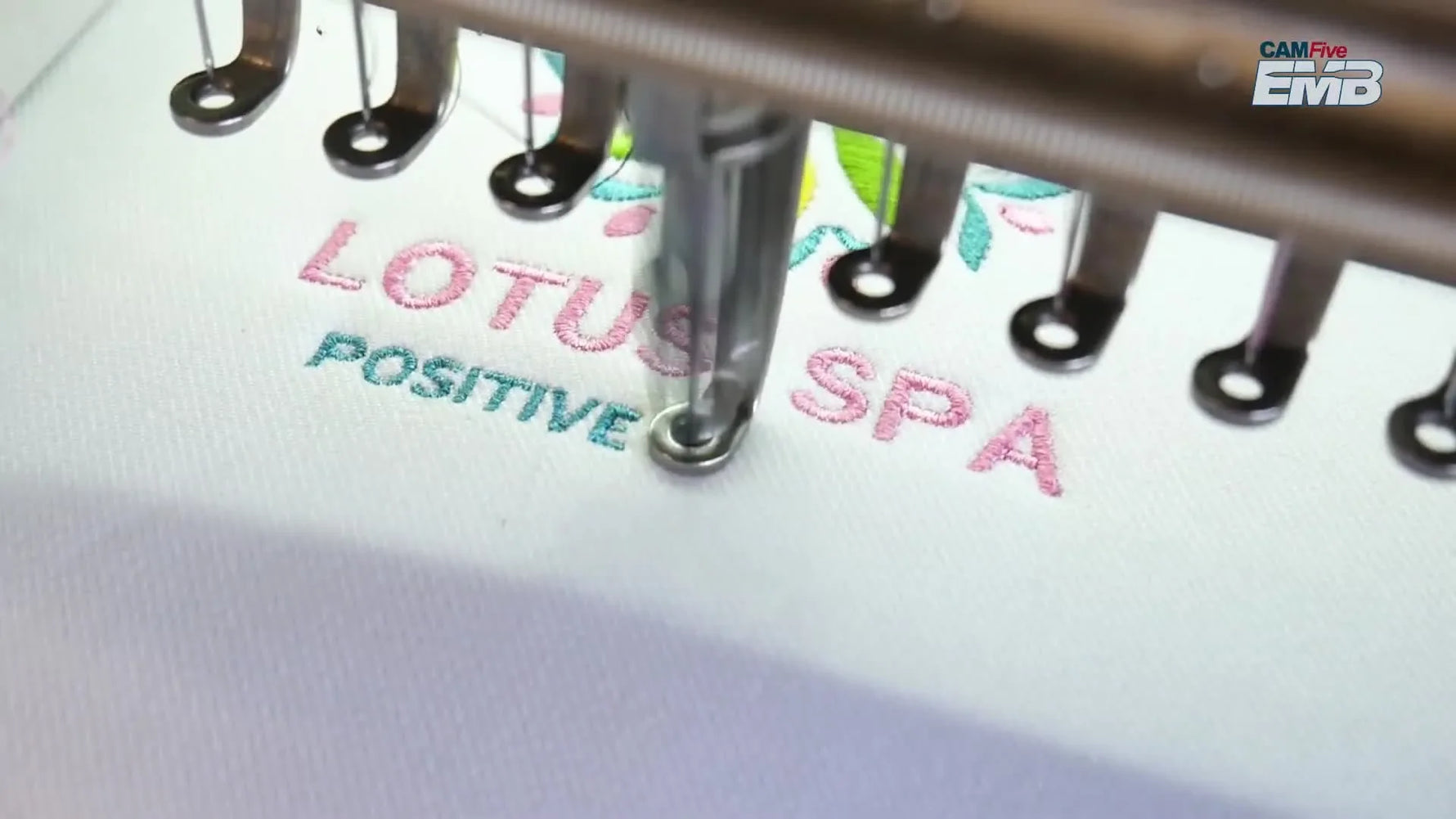 A close-up of a clean, professional manual-digitized logo stitched on textured white fabric, showing sharp edges and readable lettering.