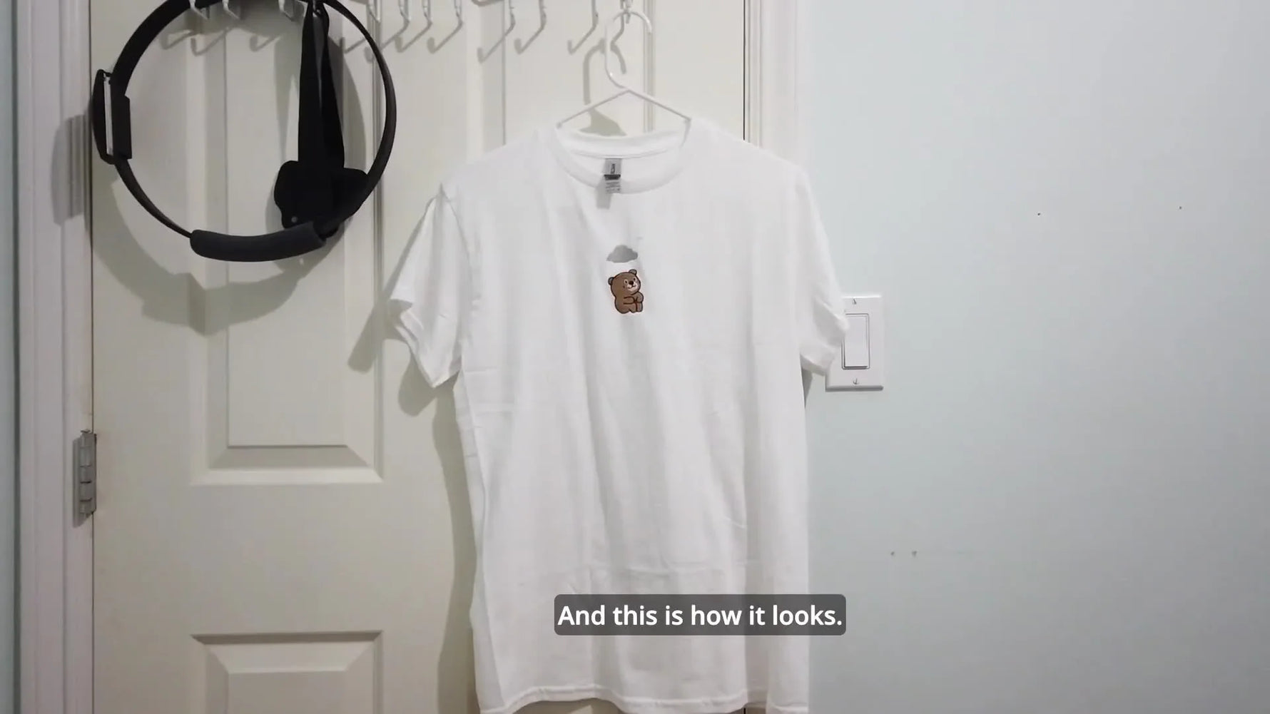 A finished white Gildan t-shirt hangs neatly, showing a clean embroidered bear design centered on the chest.
