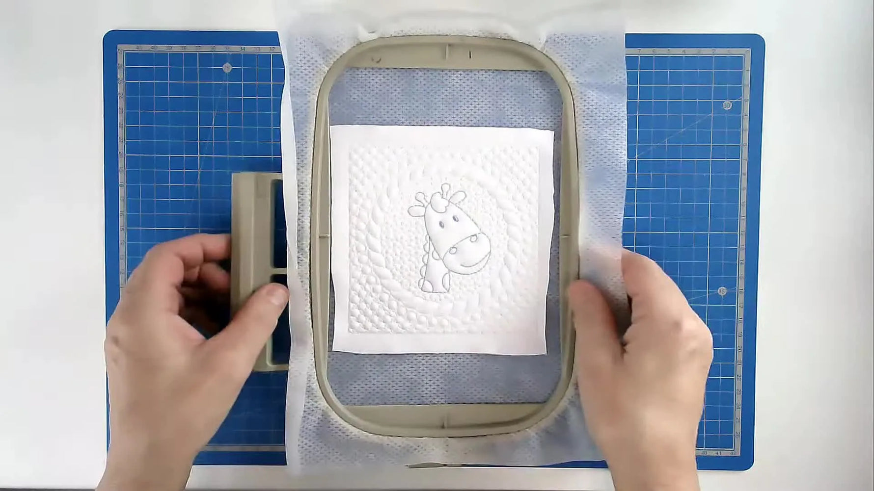 A finished giraffe quilt block sits in the 5x7 hoop, showing the trapunto texture and clean stitch definition.