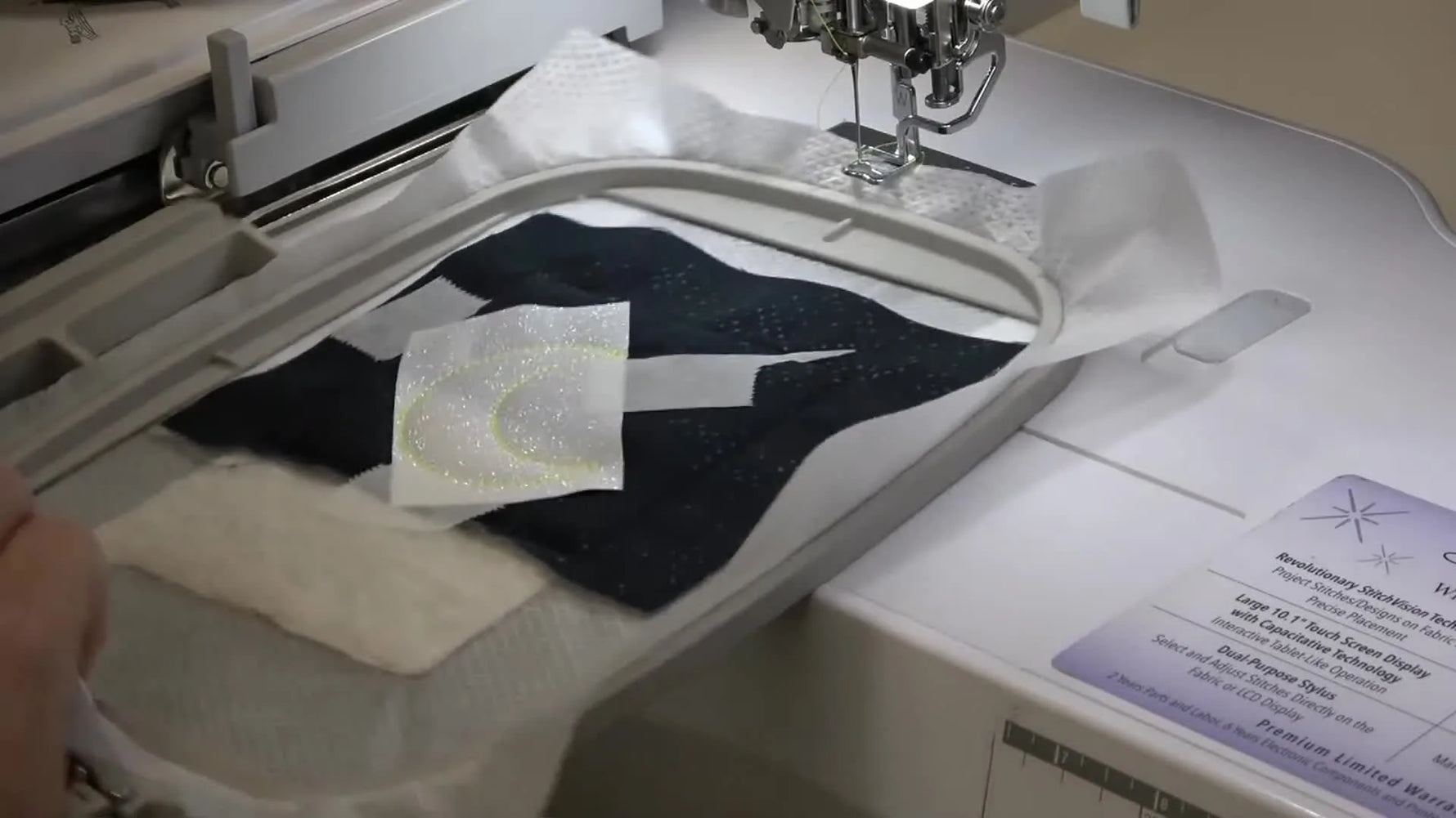 A close-up of the Brother Luminaire stitching a smooth satin border around the glitter vinyl moon appliqué.