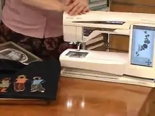 A Husqvarna Viking embroidery machine with a large touch screen display, shown as the center of a software-and-hoop workflow.