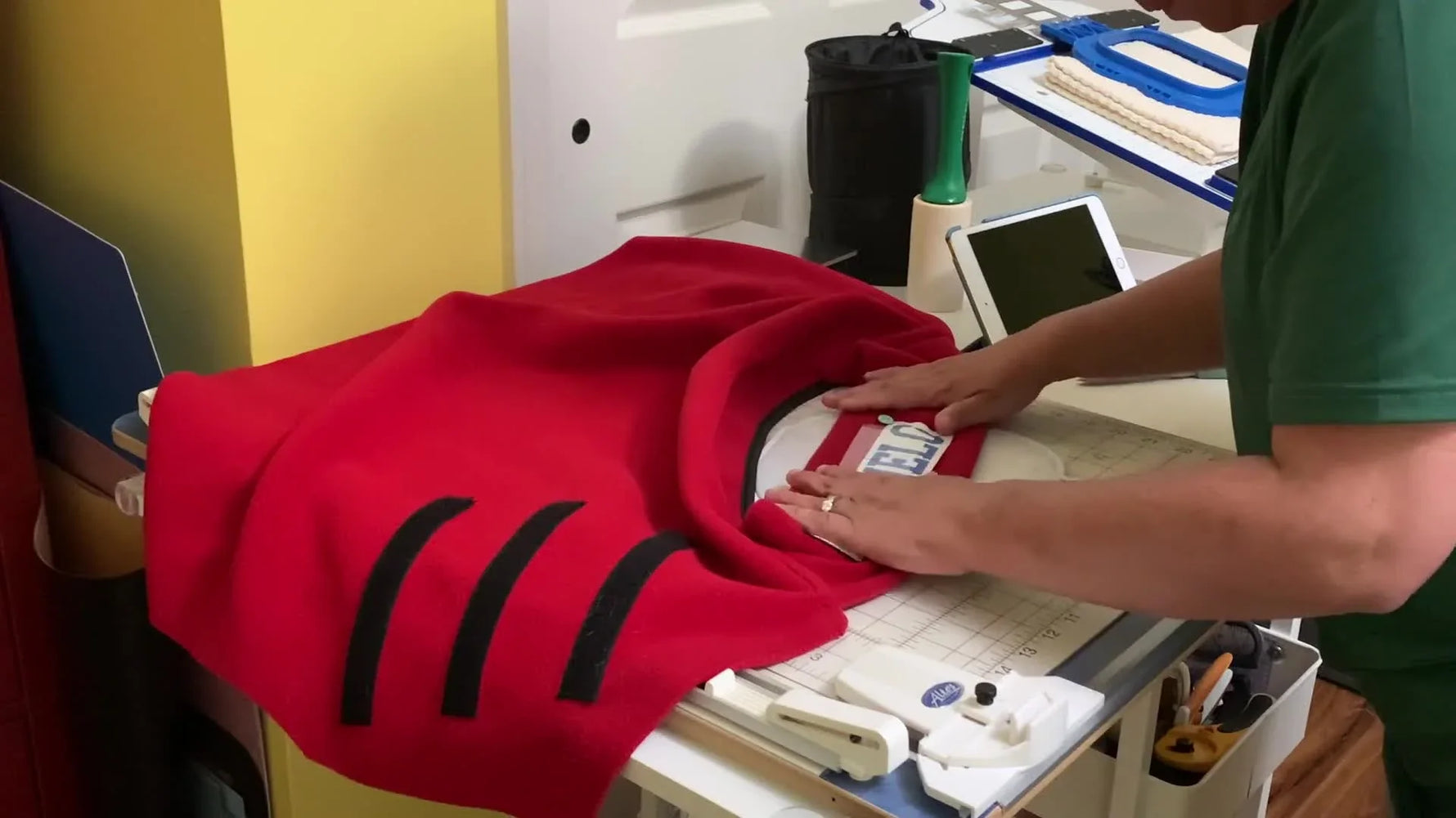 A close-up of a blue magnetic hoop snapped firmly over a red fleece dog jacket, holding the fabric securely for embroidery.
