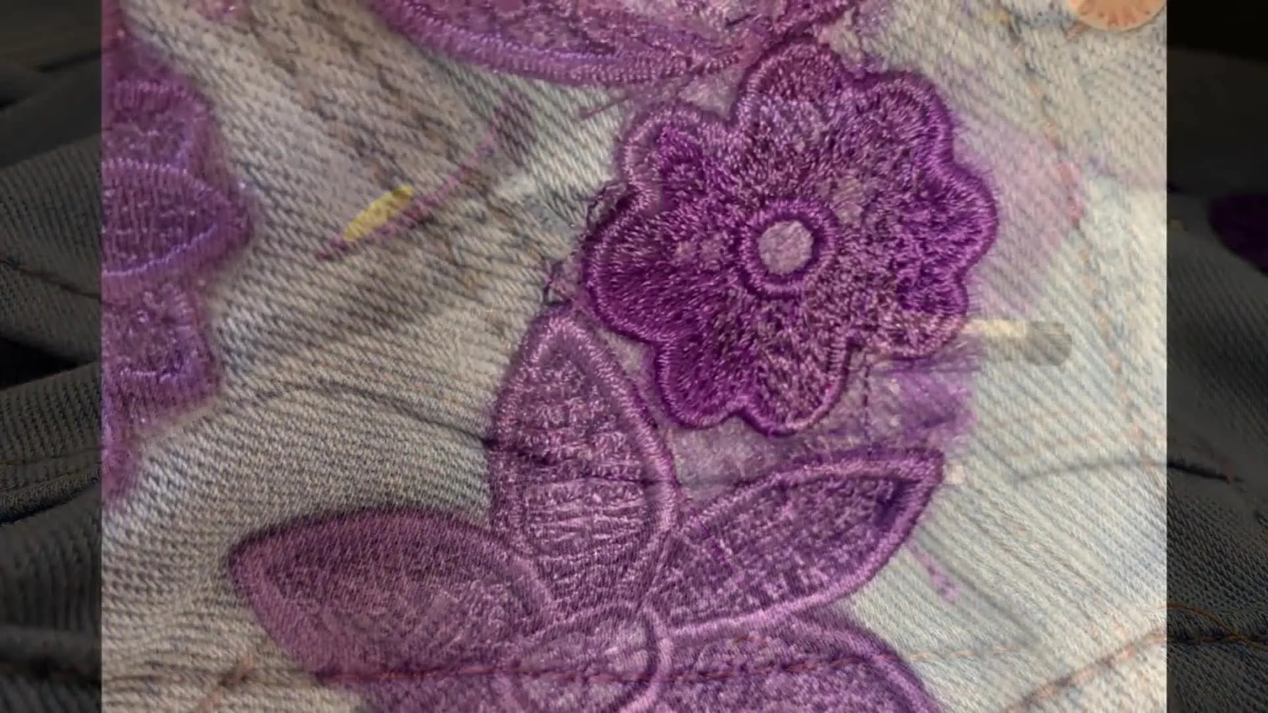 Finished jeans laid flat with a bold purple lace panel stitched down the leg, fully covering the damaged area.