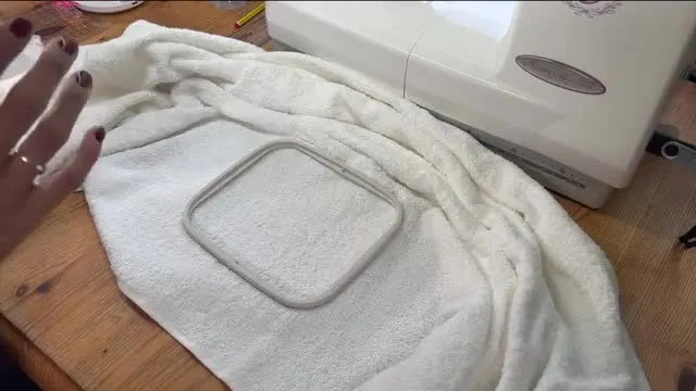 A clear water-soluble film topping is placed over a terry towel inside the hoop to keep stitches from sinking into the loops.