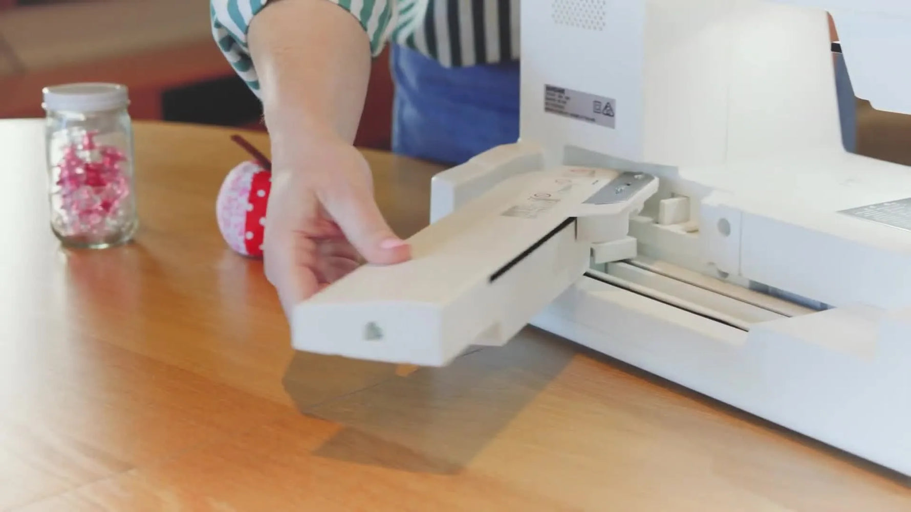 The Janome Memory Craft 1000’s embroidery arm is swung out to the left, revealing the free-arm space used for embroidering small tubular items.