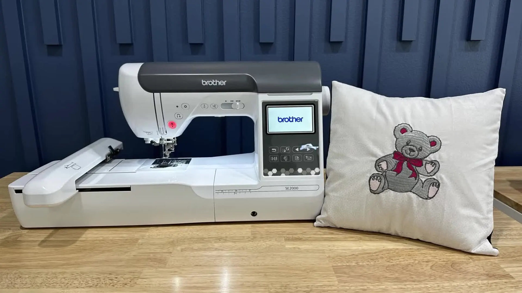 A wide shot of the Brother SE2000 beside the finished teddy bear embroidered pillow, showing the project goal and the machine used.
