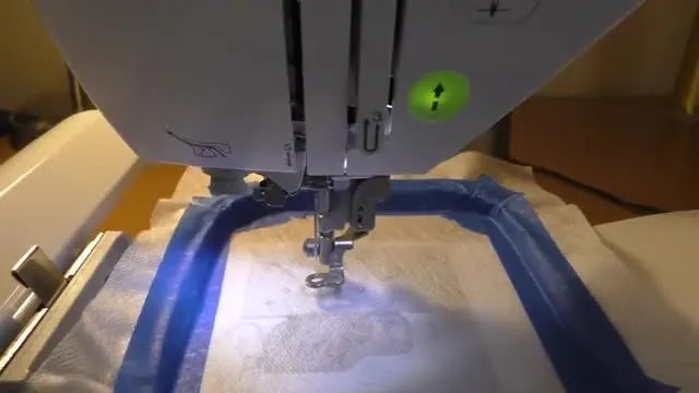 A close-up of a Brother PE-770 stitching a dense metallic snowflake lace design directly onto water-soluble stabilizer.