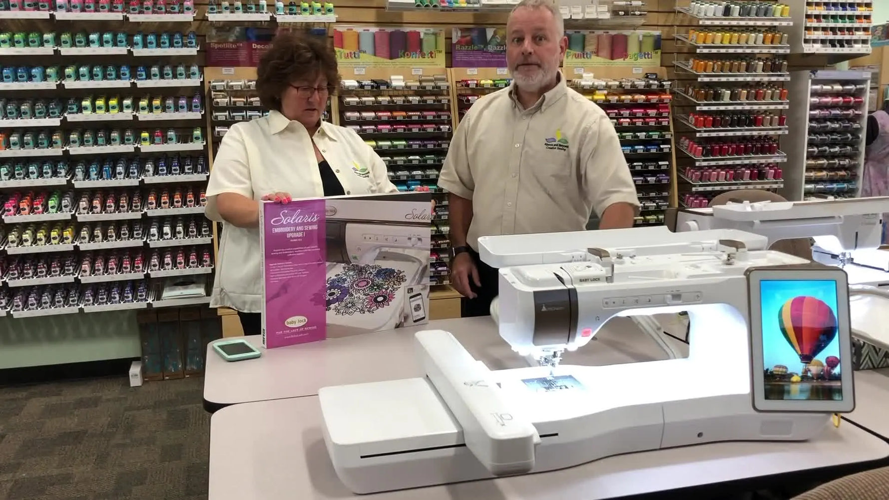 A presenter holds the oversized 10-5/8" square clamping hoop at chest level to show its scale for the Baby Lock Solaris Upgrade 1.
